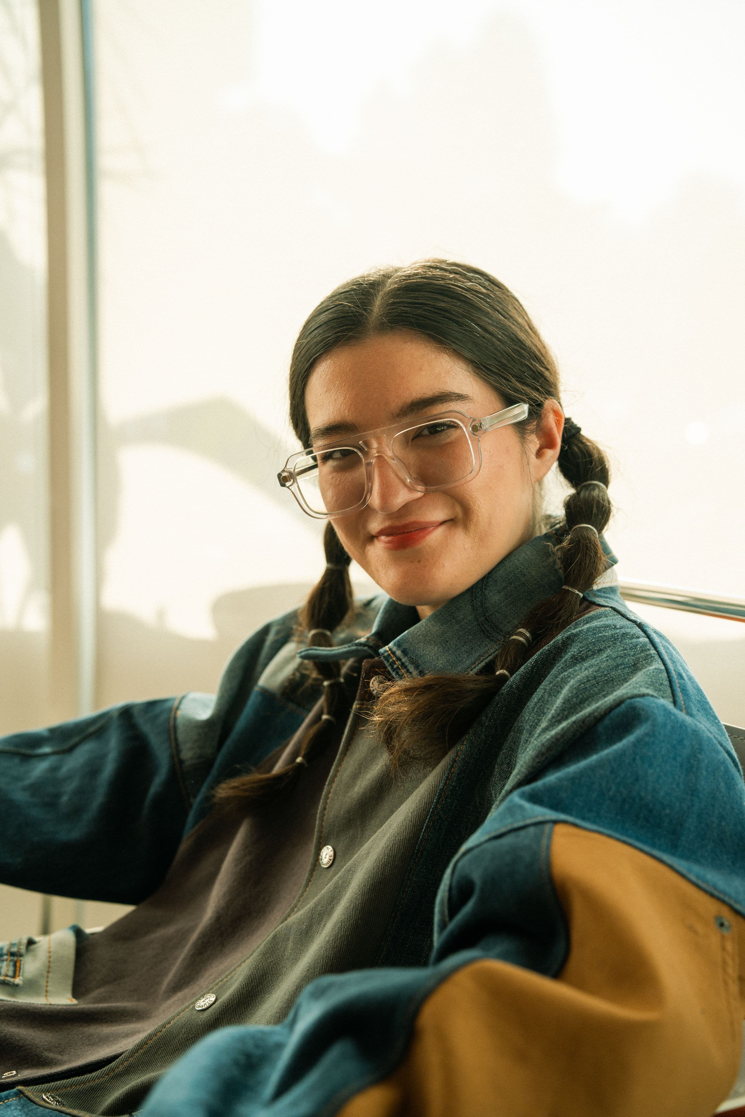 Arabelle Sicardi smiles with braids and a jean shirt with her body pointed three quarters to the camera.